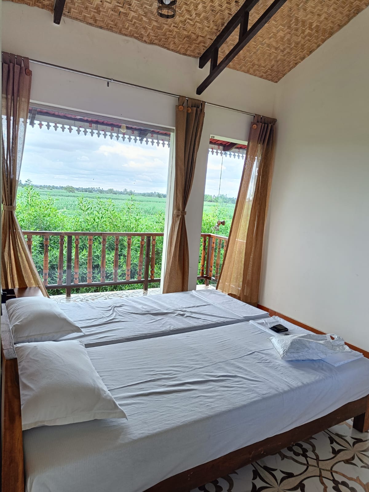 Guest bedroom with balcony overlooking the fields at Tapasya Health & Wellness